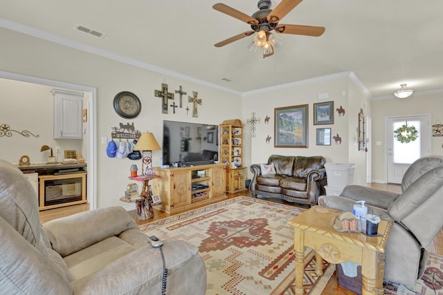 living room with crown molding, light wood-style floors, a ceiling fan, baseboards, and visible vents