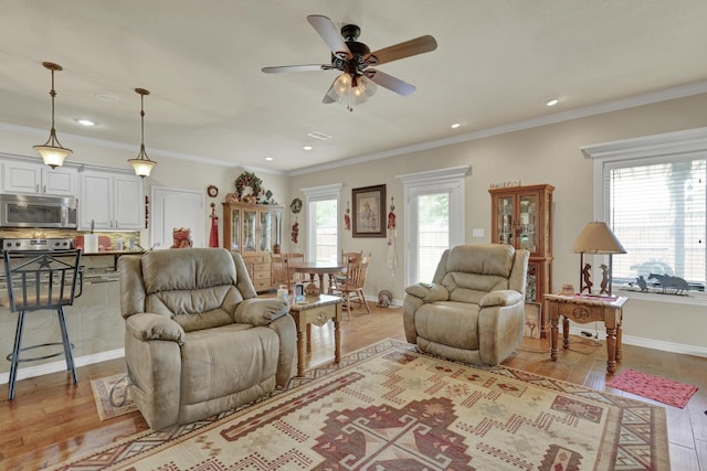 living area featuring ornamental molding, baseboards, ceiling fan, recessed lighting, and light wood-style flooring