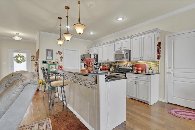 kitchen with dark countertops, a breakfast bar area, light wood-style flooring, stainless steel appliances, and backsplash