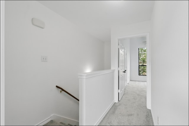 corridor with baseboards, carpet flooring, and an upstairs landing