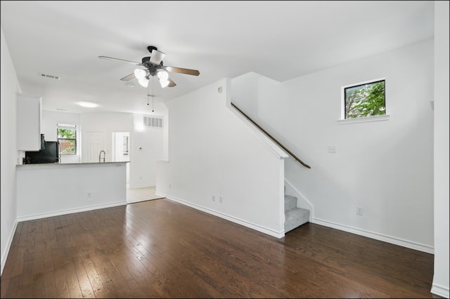 unfurnished living room with ceiling fan, stairs, baseboards, visible vents, and hardwood / wood-style flooring