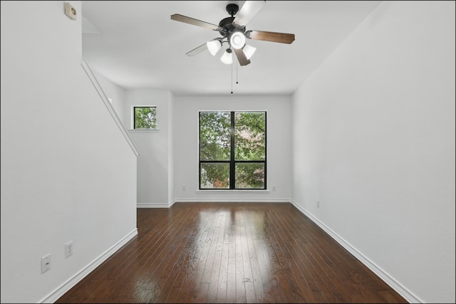 unfurnished room featuring dark wood-style flooring, a ceiling fan, and baseboards