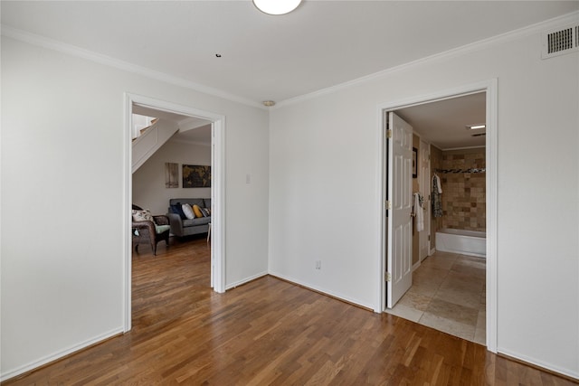 empty room with visible vents, ornamental molding, and wood finished floors