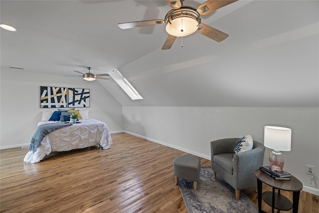 bedroom featuring baseboards, ceiling fan, wood finished floors, and vaulted ceiling with skylight