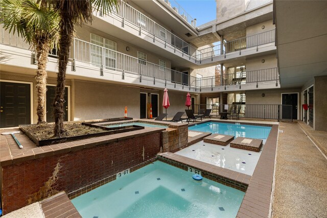 community pool with a hot tub and a patio area