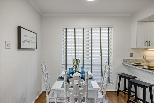 dining room featuring dark wood-style flooring, baseboards, and ornamental molding