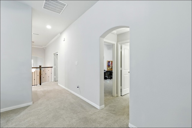 hall featuring visible vents, arched walkways, crown molding, and light carpet