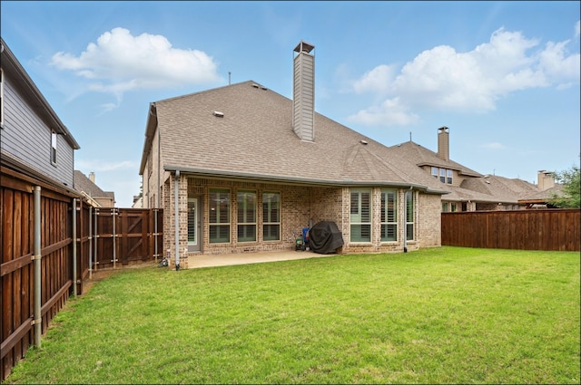 rear view of property with a shingled roof, brick siding, a fenced backyard, a patio, and a yard