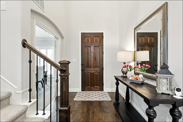 foyer with visible vents, baseboards, dark wood-style floors, and stairway