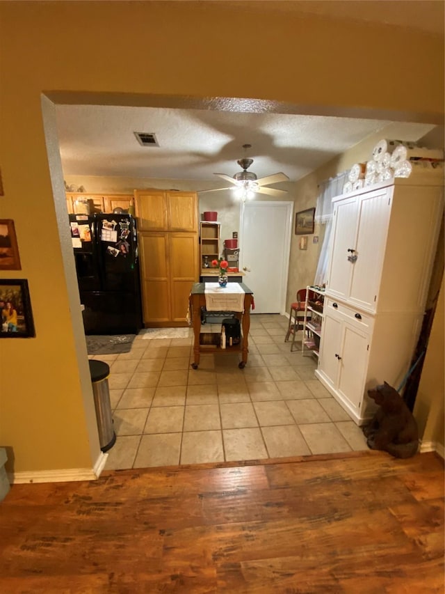 dining space with ceiling fan, a textured ceiling, baseboards, light wood-type flooring, and visible vents