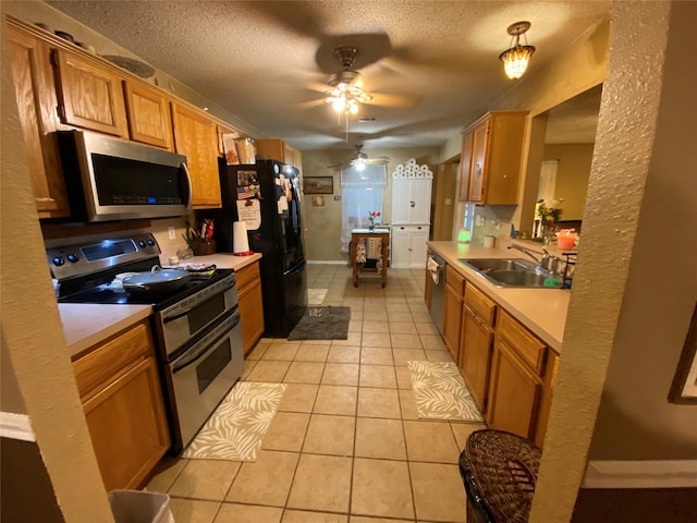 kitchen with light tile patterned flooring, a sink, light countertops, stainless steel appliances, and a ceiling fan
