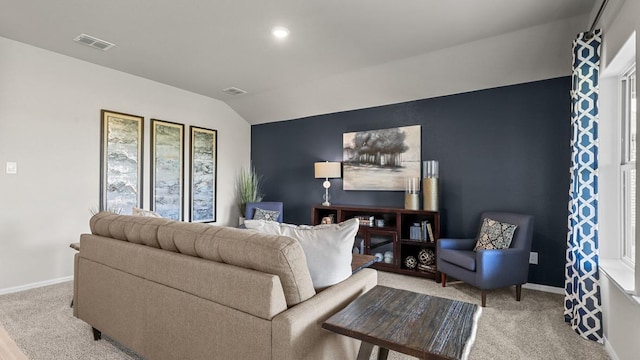 carpeted living room with baseboards, visible vents, and vaulted ceiling