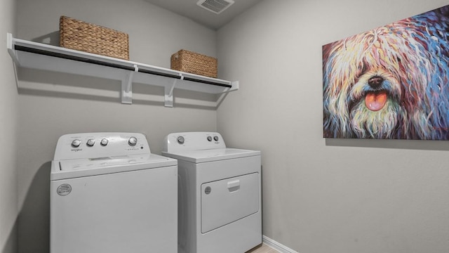 clothes washing area featuring separate washer and dryer, laundry area, visible vents, and baseboards