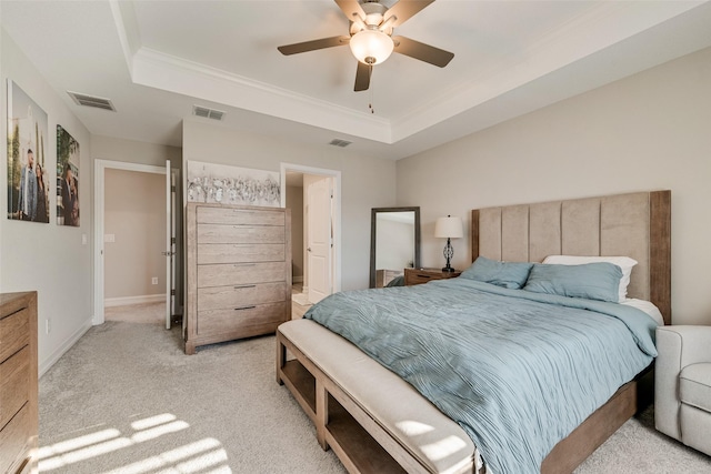 bedroom featuring light colored carpet, a tray ceiling, and visible vents