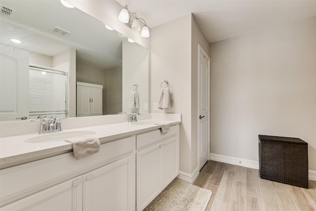 full bath with a sink, a shower stall, double vanity, and visible vents