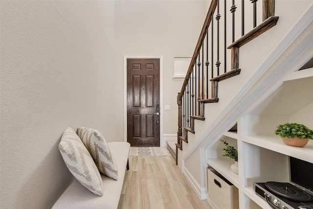 entryway with baseboards, stairs, and light wood-style flooring