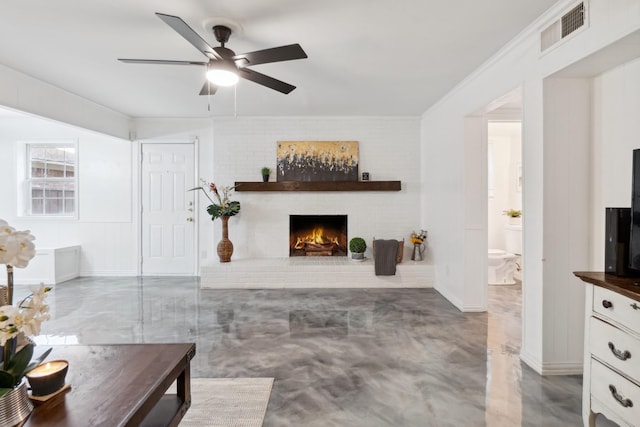 living room featuring ceiling fan, a fireplace, and concrete floors