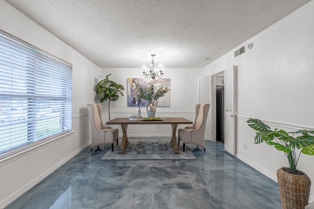 dining area featuring concrete flooring, a chandelier, a textured ceiling, and baseboards