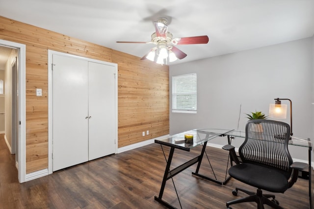 home office featuring wood walls, ceiling fan, dark wood-style floors, and baseboards
