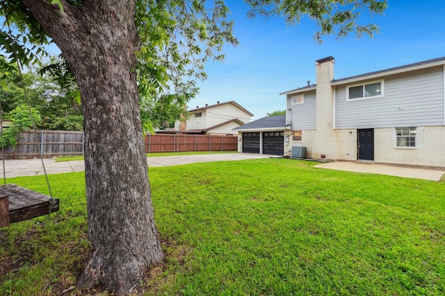 view of yard featuring central AC unit, an attached garage, concrete driveway, and a patio area