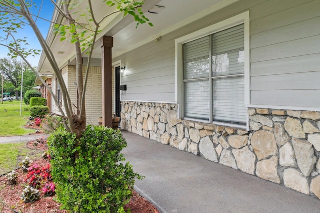 entrance to property with stone siding and a porch
