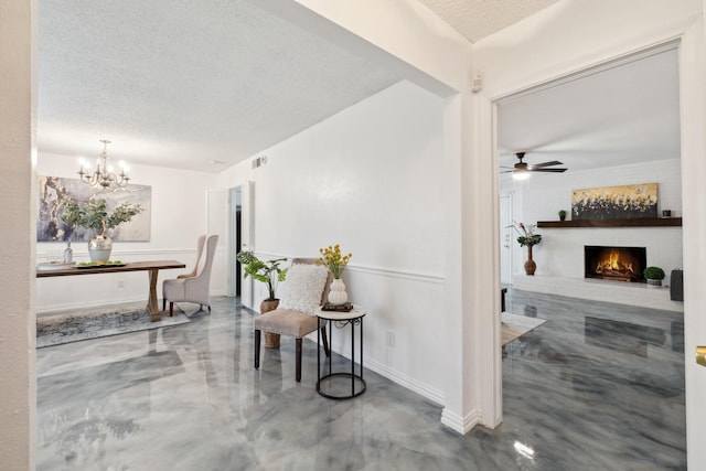 hallway featuring a textured ceiling, a chandelier, baseboards, and concrete flooring