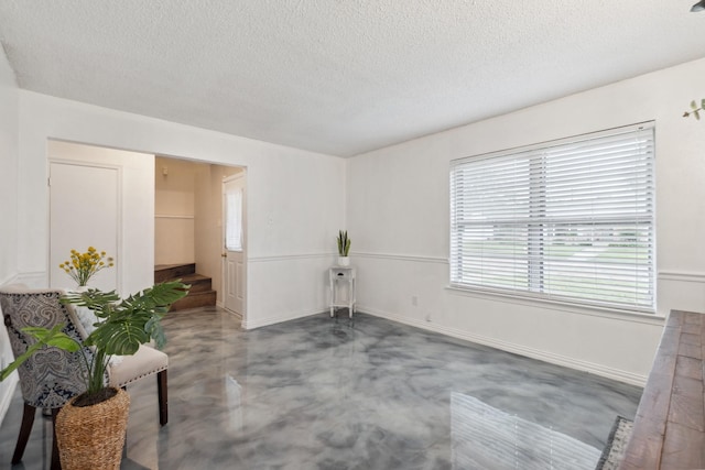 empty room with concrete flooring, a textured ceiling, and baseboards