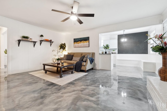 living area with ceiling fan, finished concrete floors, and baseboards