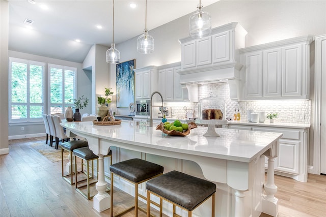 kitchen featuring visible vents, a breakfast bar area, backsplash, and light wood-type flooring