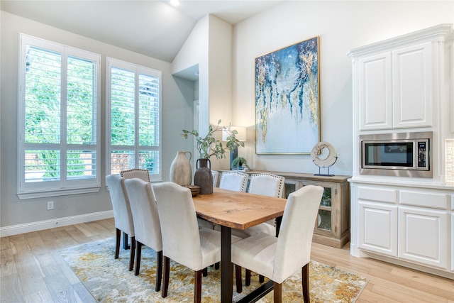 dining area with baseboards, lofted ceiling, and light wood finished floors