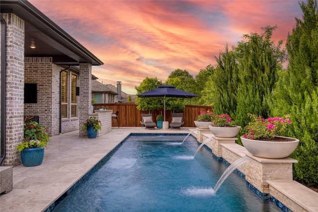 pool at dusk with a fenced in pool, fence, and a patio area