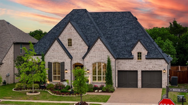 view of front of house featuring a shingled roof, brick siding, a garage, cooling unit, and driveway