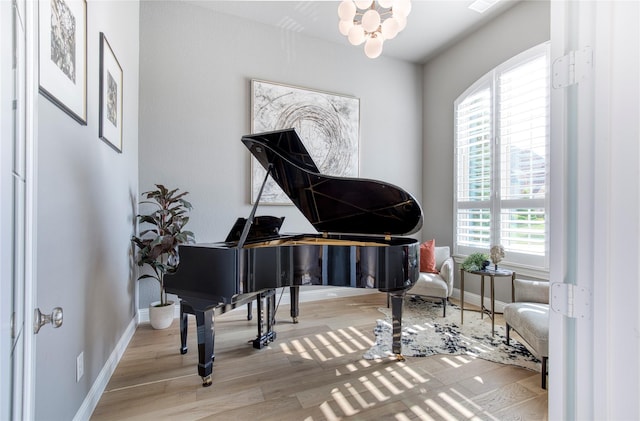 living area with baseboards, wood finished floors, and a chandelier