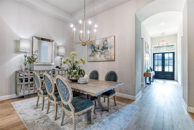 dining area with an inviting chandelier, light wood-style floors, and baseboards