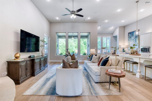 living room with plenty of natural light, light wood finished floors, and ceiling fan