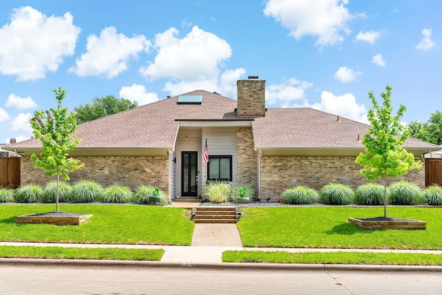 view of front of home with fence, a chimney, a front lawn, and brick siding