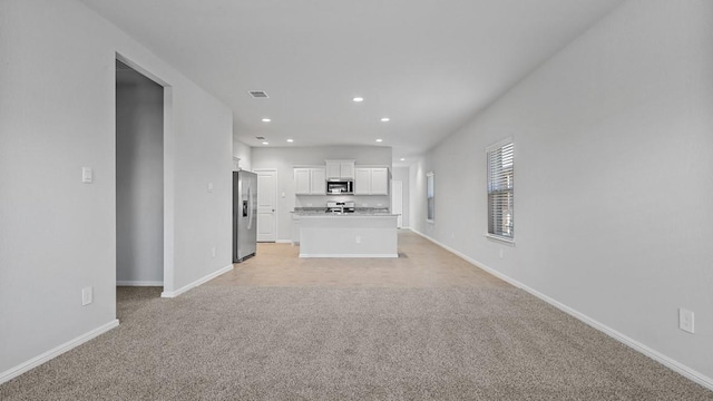 unfurnished living room featuring baseboards, visible vents, recessed lighting, and light colored carpet