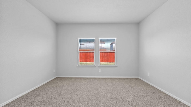carpeted spare room featuring baseboards