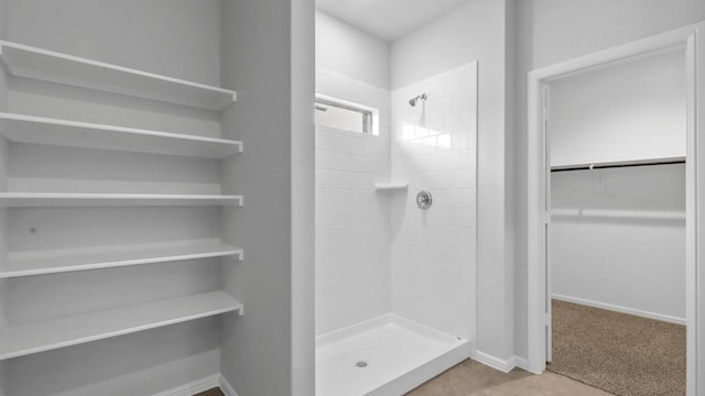 full bathroom with baseboards, a walk in closet, and a stall shower