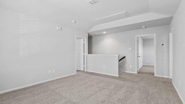 carpeted spare room with visible vents, attic access, and baseboards