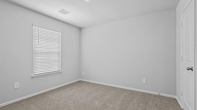 carpeted empty room featuring baseboards and visible vents