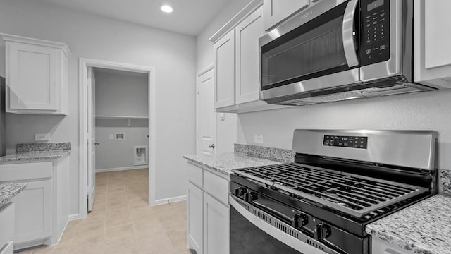 kitchen featuring appliances with stainless steel finishes, light stone countertops, light tile patterned floors, recessed lighting, and white cabinetry