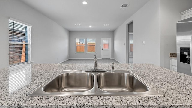 details featuring a sink, white cabinets, light stone countertops, and visible vents
