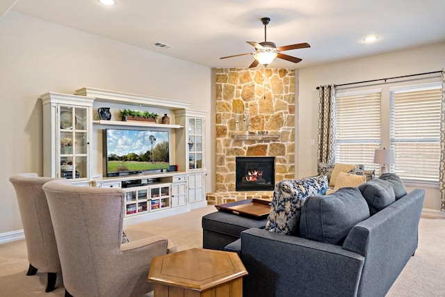 living room featuring light carpet, a stone fireplace, a ceiling fan, recessed lighting, and visible vents