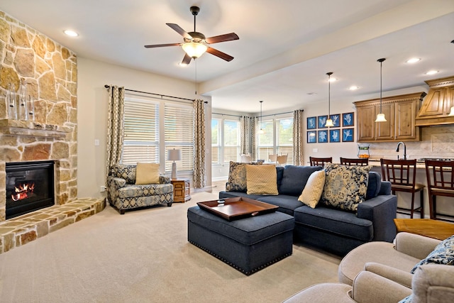 living area featuring a ceiling fan, light colored carpet, recessed lighting, and a fireplace