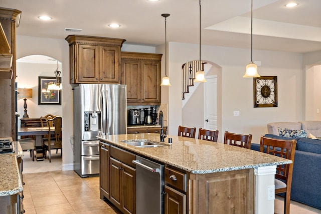 kitchen featuring a sink, arched walkways, a breakfast bar area, and stainless steel appliances