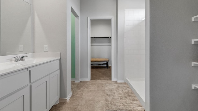 bathroom featuring vanity, tile patterned flooring, a textured wall, a spacious closet, and a stall shower