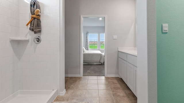 ensuite bathroom with tile patterned flooring, vanity, baseboards, ensuite bath, and tiled shower