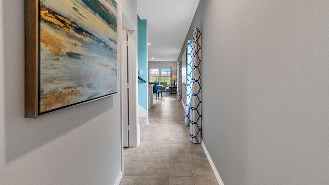 hall featuring light tile patterned floors, baseboards, and recessed lighting