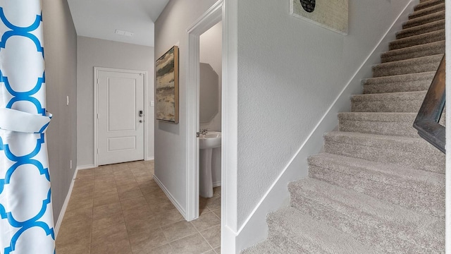 stairway featuring tile patterned floors, visible vents, and baseboards